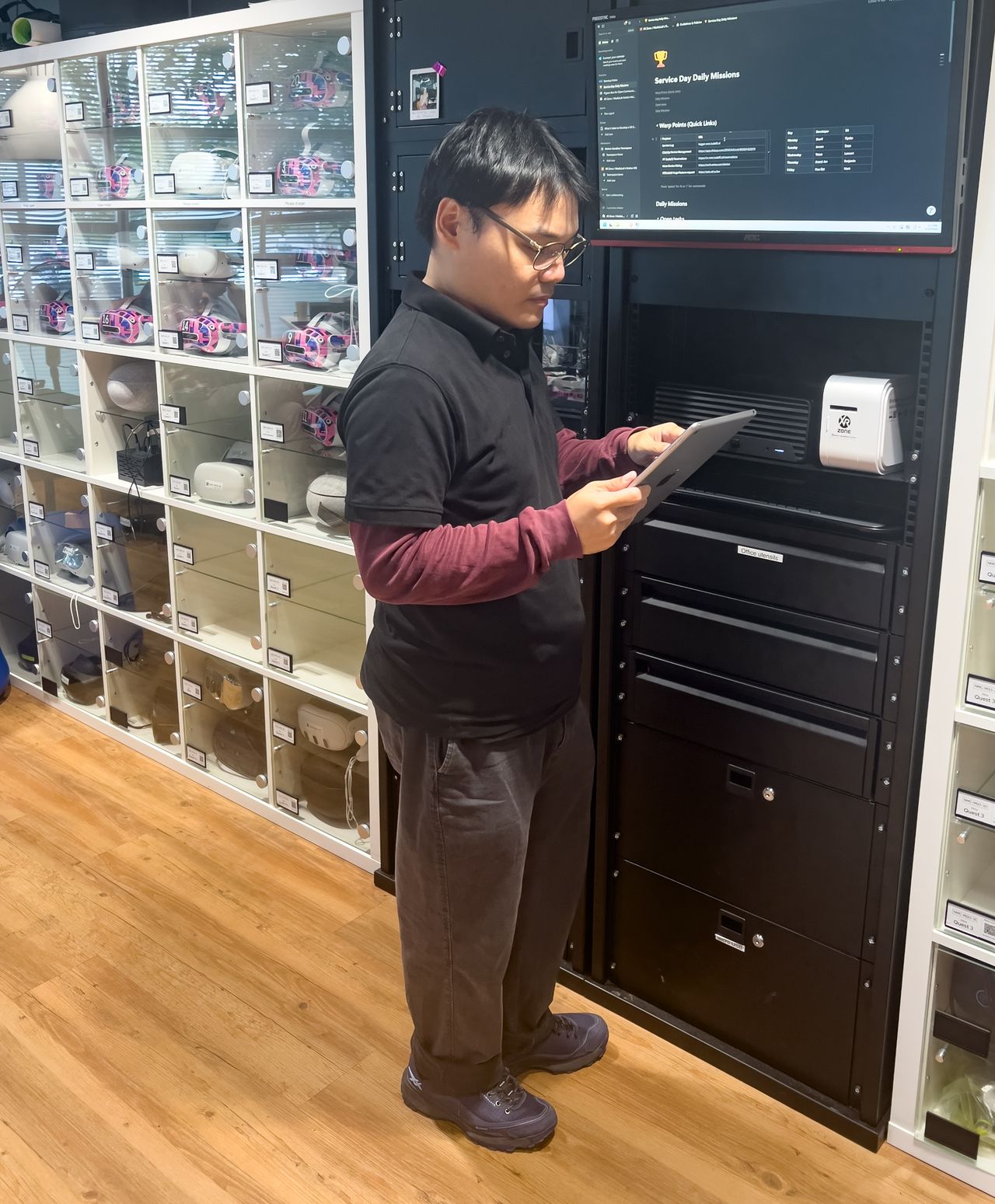 An XR operator managing headsets with a tablet beside equipment storage